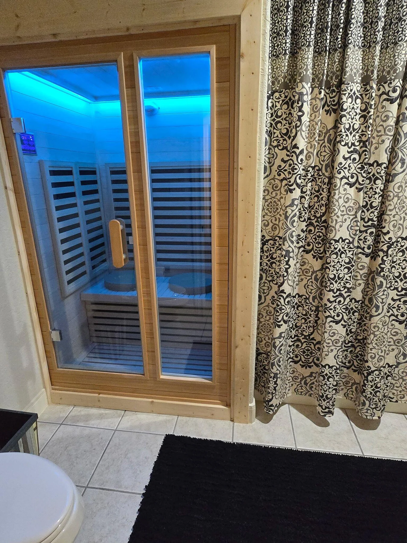 Completed sauna conversion with a wood-framed glass door and blue interior lighting
