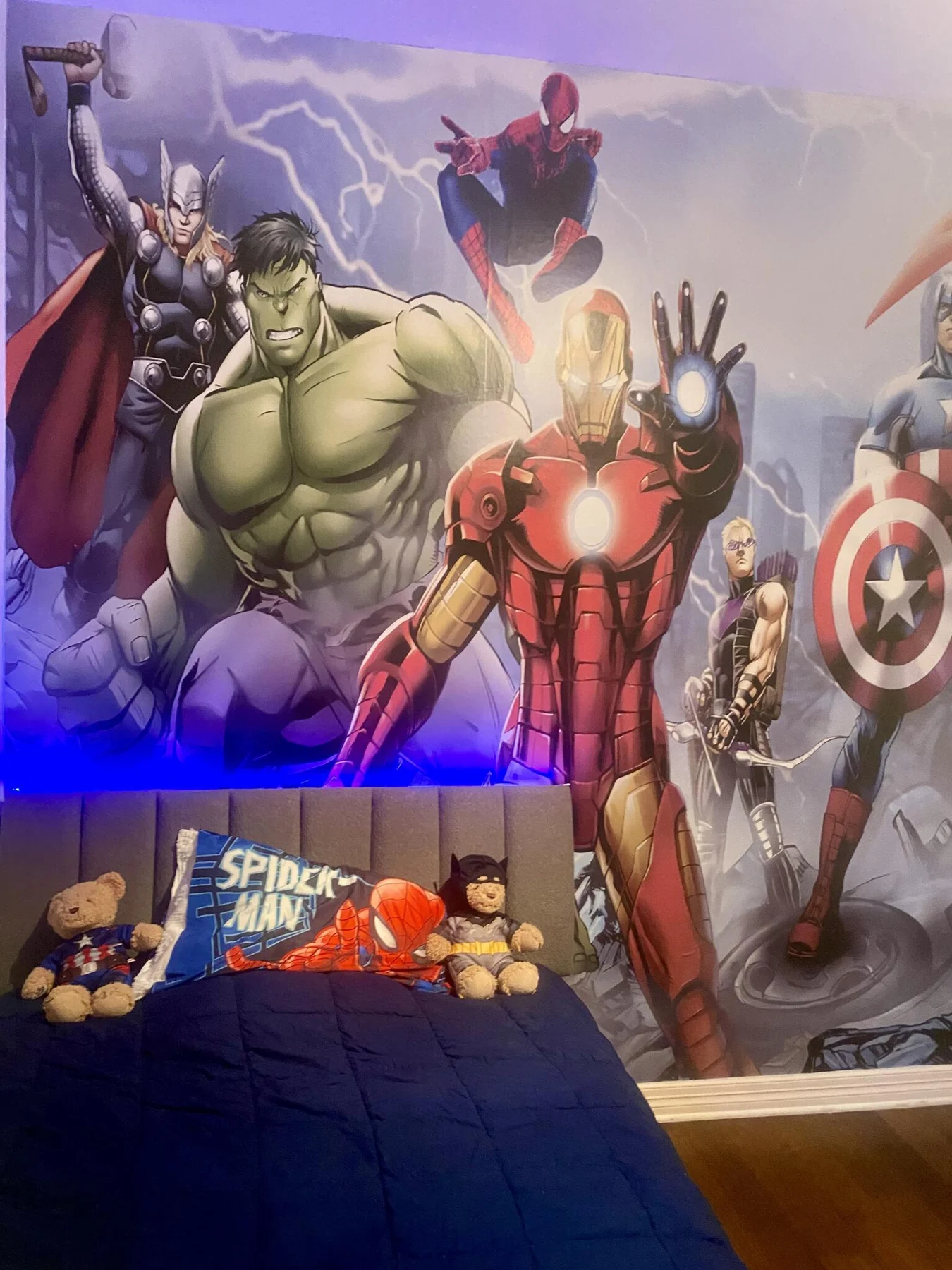 Installed superhero wallpaper behind a bed